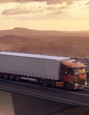 A right-hand-drive Renault Trucks T High pulls a semi-trailer across the Millau Viaduct at sunset, overlooking a spectacular sea of clouds.